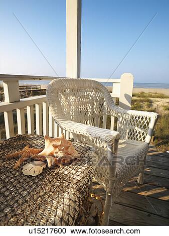 Still life shot of a wicker chair and sea shells on table with beach in background. View Large Photo Image Stock Image - Still life shot of a wicker chair and sea shells on table with beach in background.. Fotosearch