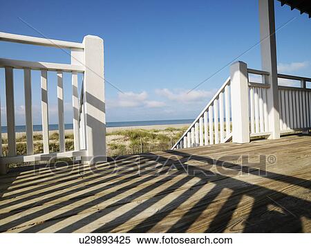 View of beach from porch with railing casting shadow on wooden deck at Bald Head Island, North Carolina View Large Photo Image Stock Photography - View of beach from porch with railing casting shadow on wooden deck at Bald Head Island, North Carolina. Fotosearch