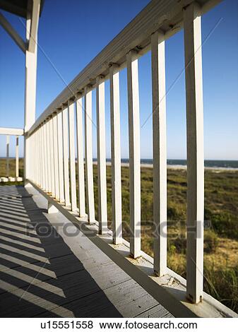 Stock Photo - Wooden railing on porch overlooking beach at Bald Head Island, North Carolina. Fotosearch