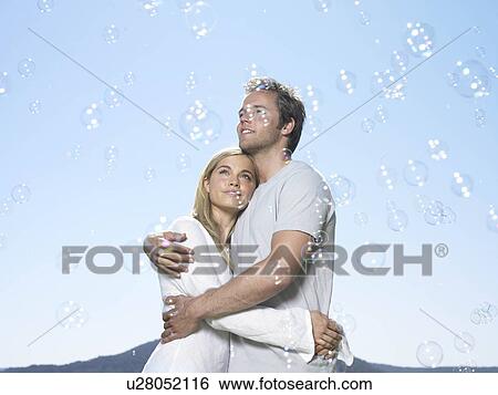 Couple looking at bubbles in sun View Large Photo Image Stock Photograph - Couple looking at bubbles in sun. Fotosearch