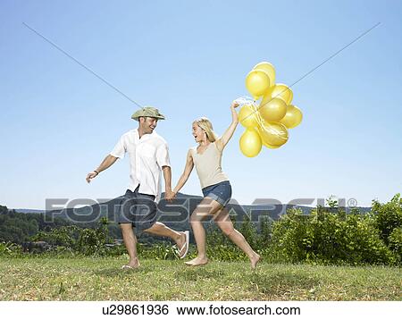 Couple running with balloons View Large Photo Image Stock Photograph - Couple running with balloons. Fotosearch