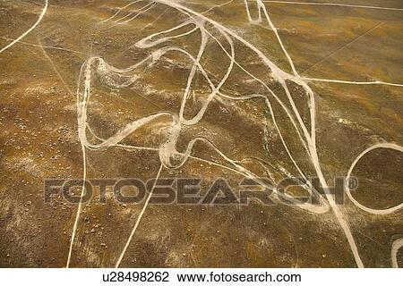 Stock Image - Aerial of barren landscape with dirt road trails in California, USA. Fotosearch