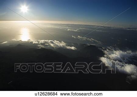 Aerial view of Maui, Hawaii coast with sun over Pacific ocean and mountainous landscape View Large Photo Image Picture - Aerial view of Maui, Hawaii coast with sun over Pacific ocean and mountainous landscape. Fotosearch