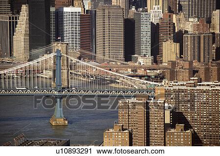Stock Image - Aerial view of New York City's Manhattan Bridge with Brooklyn Bridge and Manhattan buildings in background.. Fotosearch