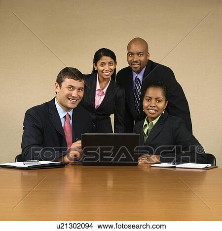 Picture - Businesspeople gathered around laptop computer smiling. Fotosearch