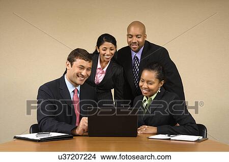 Picture - Businesspeople gathered around laptop . Fotosearch