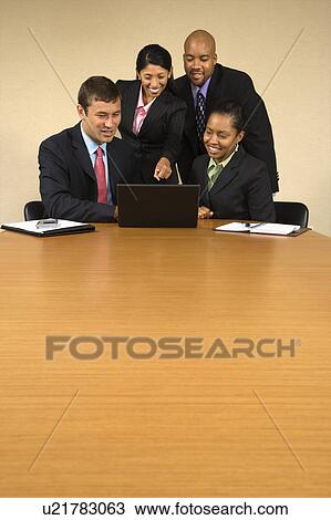 Businesspeople gathered around laptop computer looking at monitor and smiling. View Large Photo Image Stock Image - Businesspeople gathered around laptop computer looking at monitor and smiling.. Fotosearch