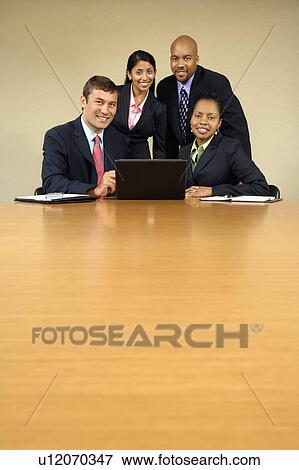 Businesspeople gathered around laptop computer smiling View Large Photo Image Stock Photo - Businesspeople gathered around laptop computer smiling. Fotosearch
