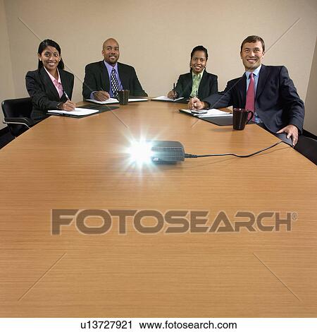 Businesspeople sitting at conference table watching LCD projector presentation. View Large Photo Image Stock Image - Businesspeople sitting at conference table watching LCD projector presentation.. Fotosearch