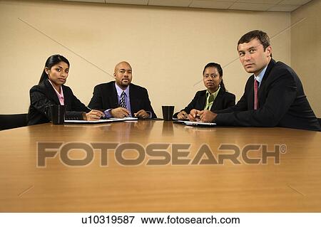 Stock Photo - Businesspeople sitting at conference table.. Fotosearch