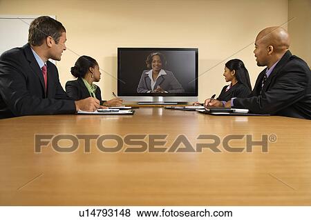 Businesspeople sitting at conference table looking at flat screen display. View Large Photo Image Stock Photo - Businesspeople sitting at conference table looking at flat screen display.. Fotosearch