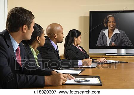 Businesspeople sitting at conference table looking at flat screen display. View Large Photo Image Stock Photo - Businesspeople sitting at conference table looking at flat screen display.. Fotosearch