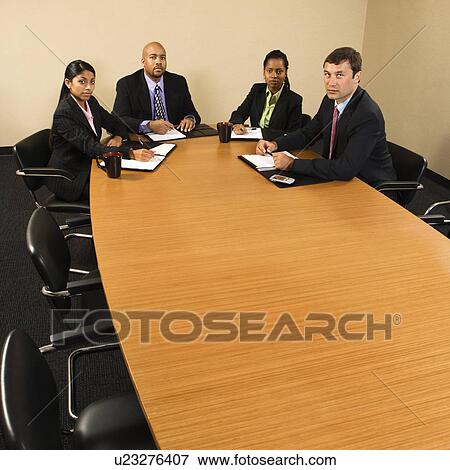 Stock Photo - Businesspeople sitting at conference table.. Fotosearch