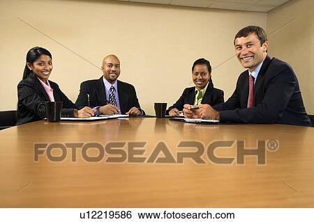 Stock Photograph - Businesspeople sitting at conference table smiling. Fotosearch