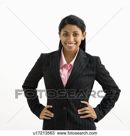 Stock Image - Portrait of smiling businesswoman with hands on hips against white background.. Fotosearch