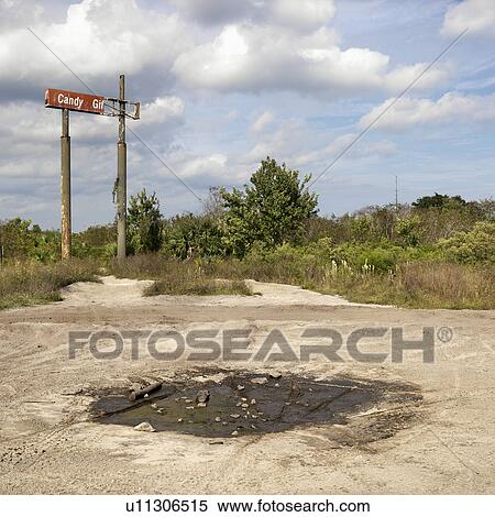 Stock Photography - Old sign in rural setting with mud puddle in foreground.. Fotosearch