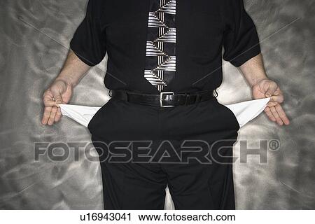 Stock Image - Caucasian mid adult man pulling out empty pants pockets.. Fotosearch