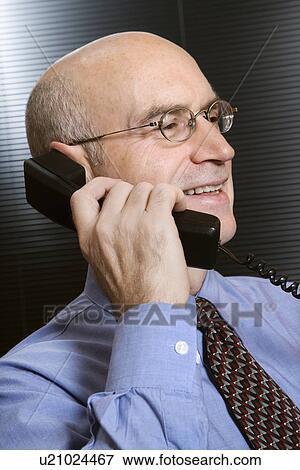 Stock Photo - Caucasian middle-aged businessman smiling and talking on telephone.. Fotosearch