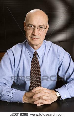 Caucasian middle-aged businessman sitting at desk in office. View Large Photo Image Stock Photography - Caucasian middle-aged businessman sitting at desk in office.. Fotosearch