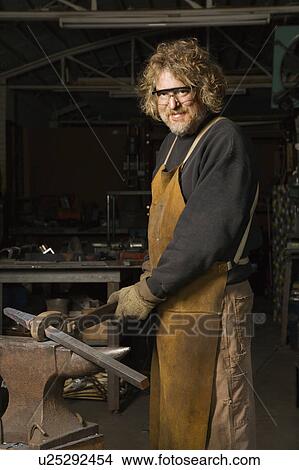 Male metalsmith holding metal on anvil View Large Photo Image Picture - Male metalsmith holding metal on anvil. Fotosearch