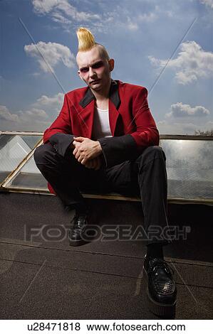 Stock Photo - Male punk sitting on a skylight on roof. Fotosearch