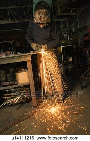 Stock Photograph - Metalsmith shaping metal and creating sparks. Fotosearch