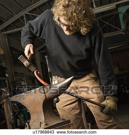 Metalsmith shaping metal on anvil View Large Photo Image Stock Image - Metalsmith shaping metal on anvil. Fotosearch