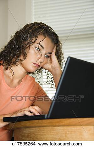 Pretty young adult brunette woman sitting and working on laptop computer View Large Photo Image Picture - Pretty young adult brunette woman sitting and working on laptop computer. Fotosearch
