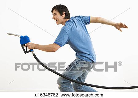 Stock Image - Asian young man aiming gasoline pump nozzle like a gun.. Fotosearch