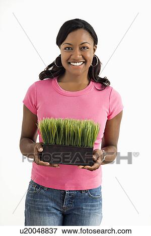 Stock Photo - Female standing holding patch of potted grass. Fotosearch