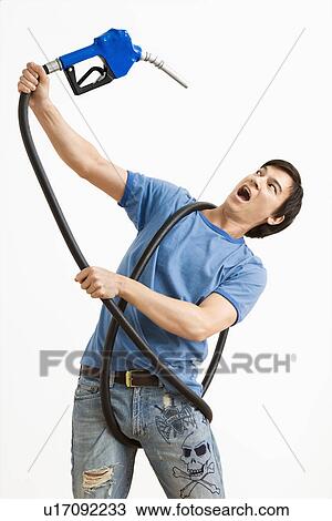 Stock Image - Man fighting with gas pump which has him entangled.. Fotosearch