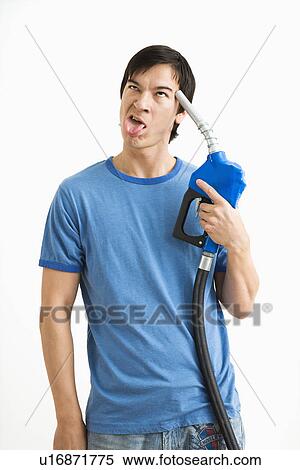 Stock Photography - Man holding gasoline pump nozzle to his forehead with disgust on his face. Fotosearch