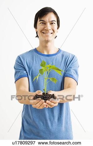 Man standing holding growing plant View Large Photo Image Stock Photo - Man standing holding growing plant. Fotosearch