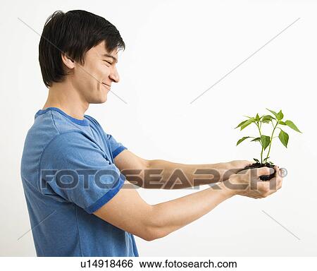Man standing holding growing plant View Large Photo Image Stock Photograph - Man standing holding growing plant. Fotosearch
