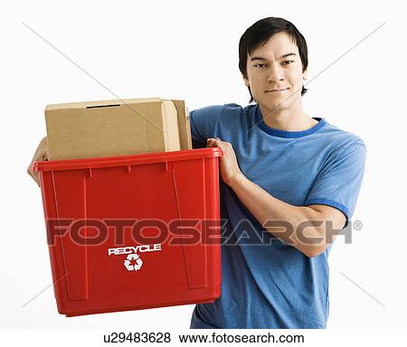 Stock Photo - Portrait of Asian young man standing holding recycling bin.. Fotosearch