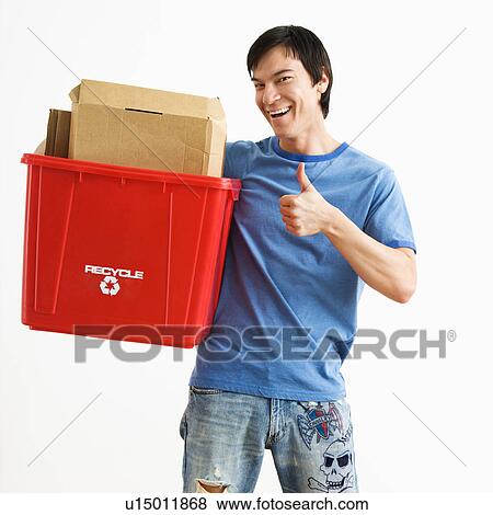 Portrait of smiling Asian young man standing holding recycling bin. View Large Photo Image Stock Photo - Portrait of smiling Asian young man standing holding recycling bin.. Fotosearch