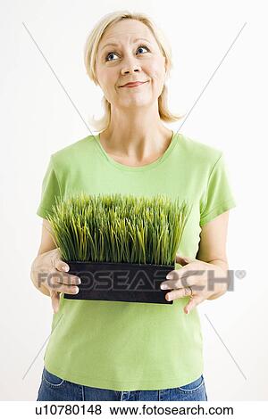 Portrait of woman holding pot of grass and looking up View Large Photo Image Stock Photo - Portrait of woman holding pot of grass and looking up. Fotosearch