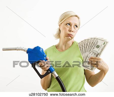 Stock Image - Woman holding gas nozzle and lots of money. Fotosearch