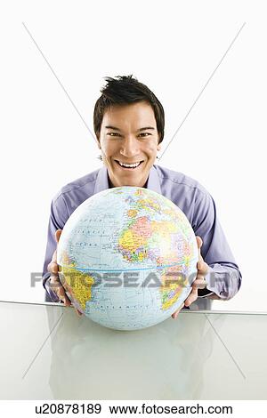 Young Asian man sitting holding globe smiling. View Large Photo Image Stock Photo - Young Asian man sitting holding globe smiling.. Fotosearch