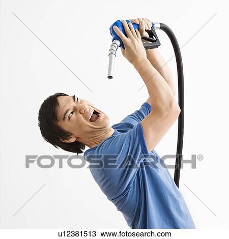 Stock Image - Young man fighting with gasoline pump nozzle. Fotosearch