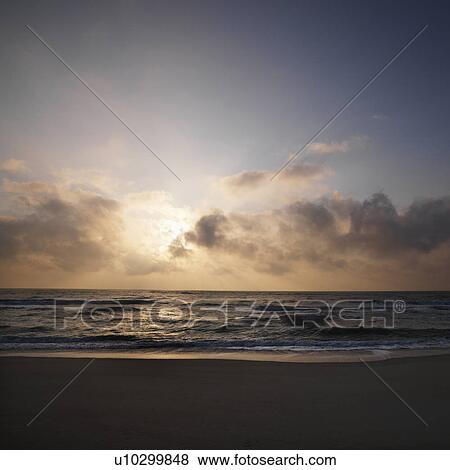 Beach with sun setting in clouds over ocean at Bald Head Island, North Carolina View Large Photo Image Stock Photo - Beach with sun setting in clouds over ocean at Bald Head Island, North Carolina. Fotosearch