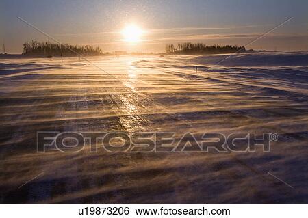 Stock Photograph - Ice covered road with sun rising in distance. Fotosearch