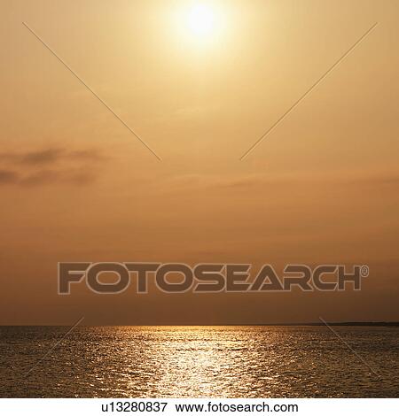 Sun over ocean with warm red tones View Large Photo Image Stock Photo - Sun over ocean with warm red tones. Fotosearch