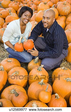Couple picking out pumpkins and smiling at outdoor market. View Large Photo Image Stock Photo - Couple picking out pumpkins and smiling at outdoor market.. Fotosearch
