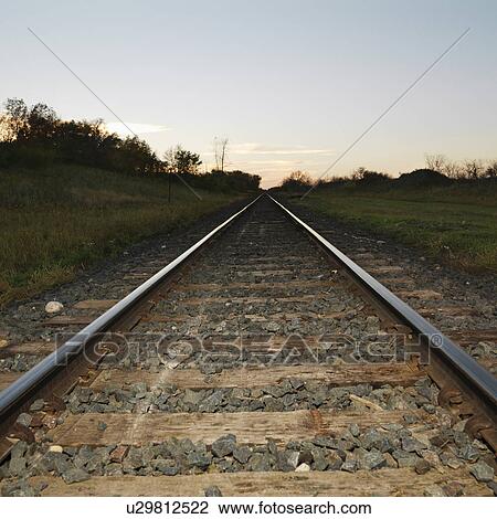 Low angle diminishing view of railroad tracks in rural setting at dusk. View Large Photo Image Stock Image - Low angle diminishing view of railroad tracks in rural setting at dusk.. Fotosearch