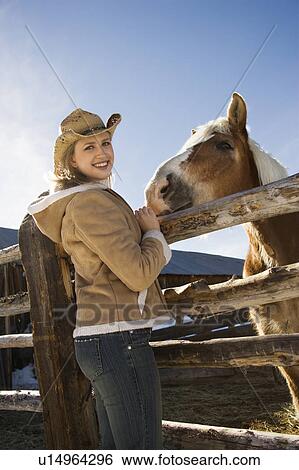 Stock Photograph - Woman standing at fence with horse . Fotosearch