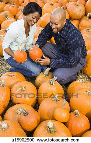 Couple picking out pumpkins and smiling at outdoor market. View Large Photo Image Stock Image - Couple picking out pumpkins and smiling at outdoor market.. Fotosearch
