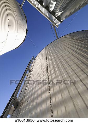 Low angle view of metal grain storage silos against blue sky. View Large Photo Image Stock Photograph - Low angle view of metal grain storage silos against blue sky.. Fotosearch