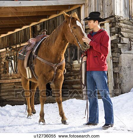 Young Caucasian man in western attire petting his horse with stable in background. View Large Photo Image Stock Photography - Young Caucasian man in western attire petting his horse with stable in background.. Fotosearch