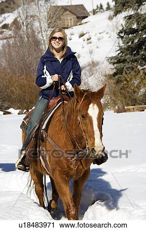 Young Caucasian woman horseback riding in snow and smiling at viewer. View Large Photo Image Stock Image - Young Caucasian woman horseback riding in snow and smiling at viewer.. Fotosearch